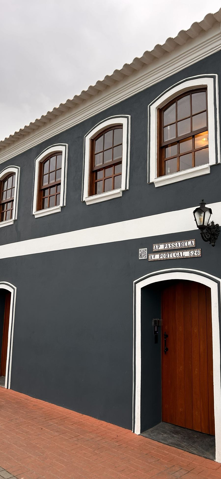 Fachada do AP Passarela na Avenida Portugal, 526: sobrado navy com janelas em arco, a placa do prédio e a porta de entrada com fechadura de código