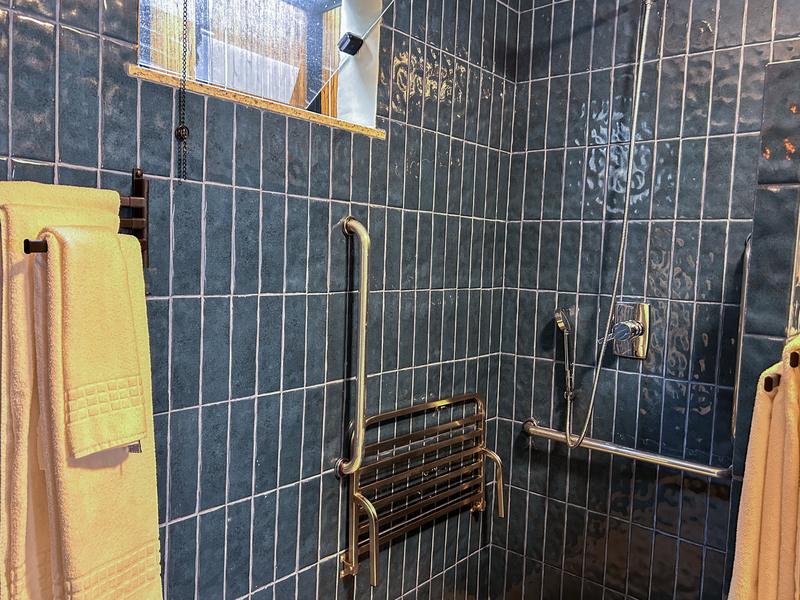 Box do banheiro do Apartamento PCD, com barras de apoio e banco fixo na parede