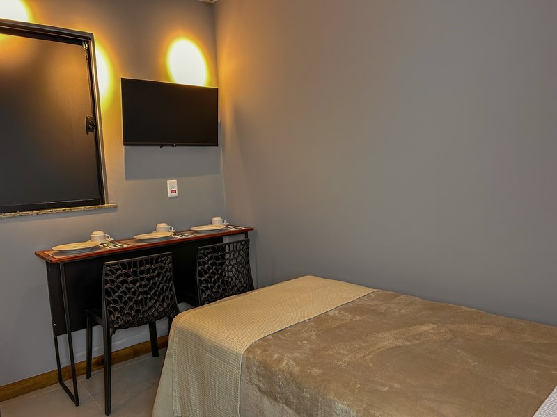 Apartamento PCD visto da cama, com a mesa de refeição e a televisão