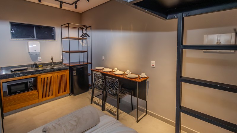 Cozinha do Standard Quádruplo vista da cama, com micro-ondas embutido e mesa de refeição